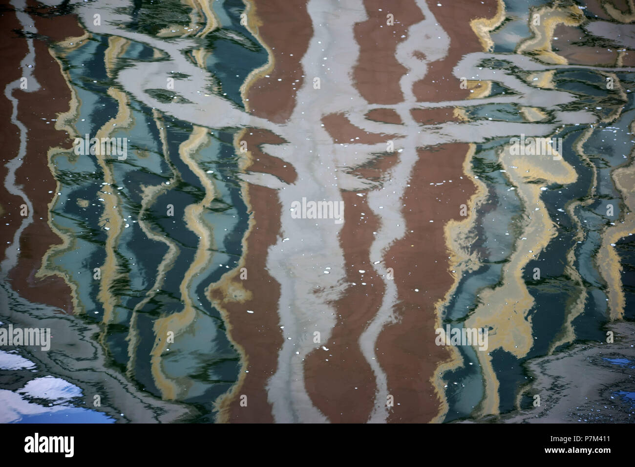 Abstrakte Überlegungen und Farbverläufe der umliegenden Infrastruktur auf der glatten Oberfläche eines Gewässers. Stockfoto