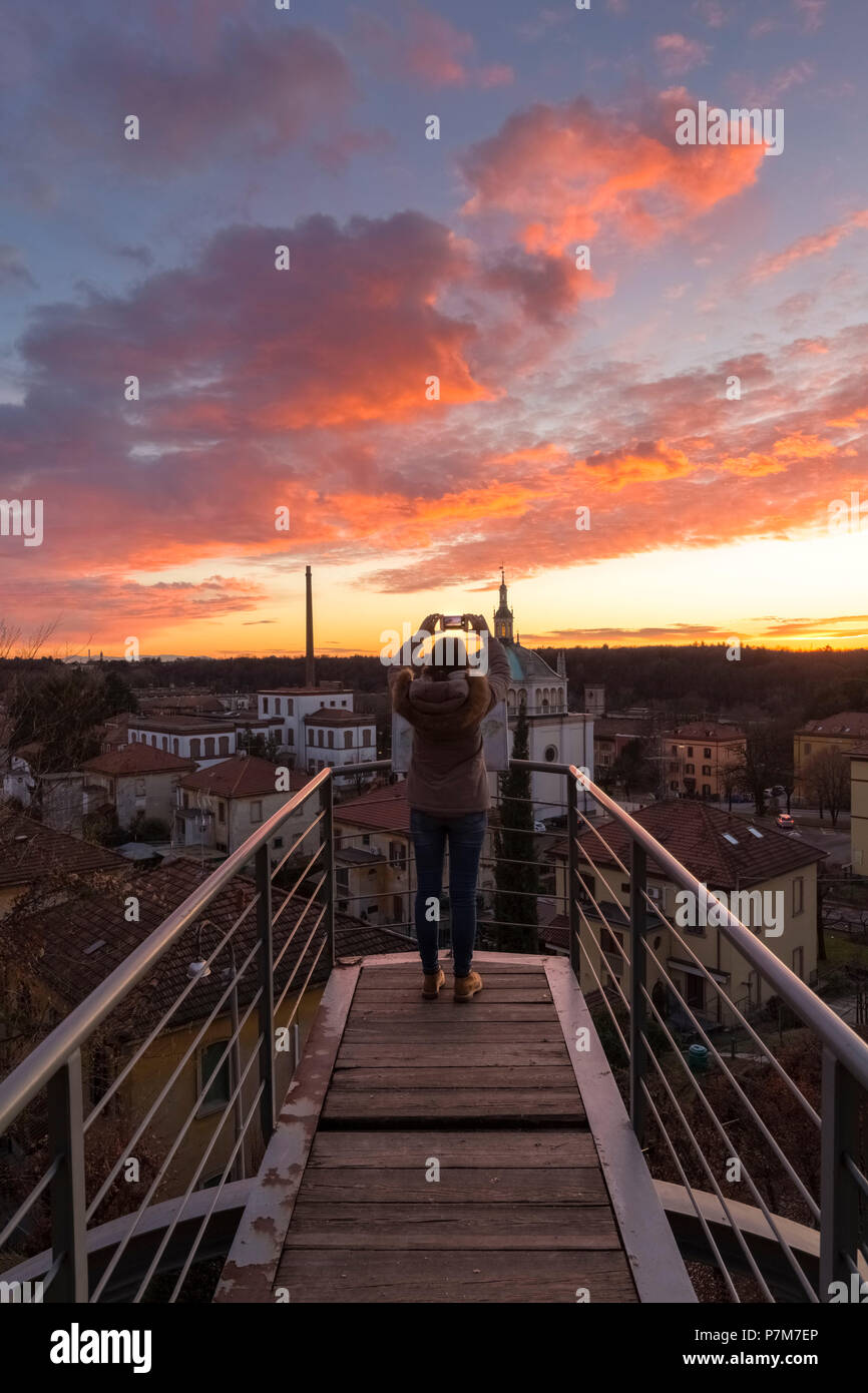 Ein turist ein Bild bei einem Sonnenuntergang auf dem Balkon über das Modell Arbeiter Dorf von Crespi d'Adda, UNESCO-Weltkulturerbe. Capriate San Gervasio, Provinz Bergamo, Lombardei, Italien. Stockfoto