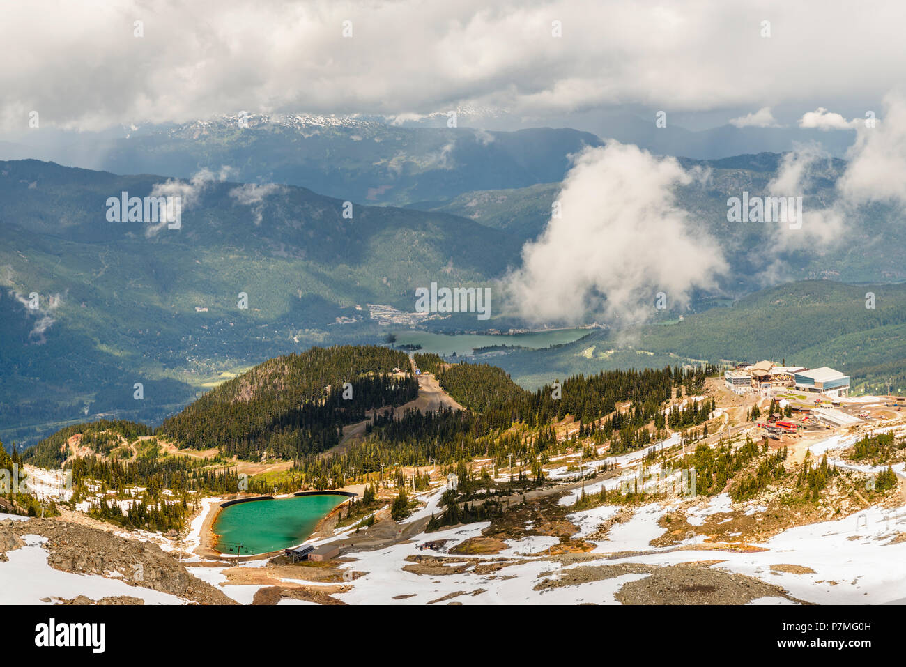 Top Aussicht auf Berge und Schnee mit Wäldern, Seen und Straßen fallen, weiße und flauschige Wolken, Gebäude auf einer Skipiste, Tourist Resort Stockfoto