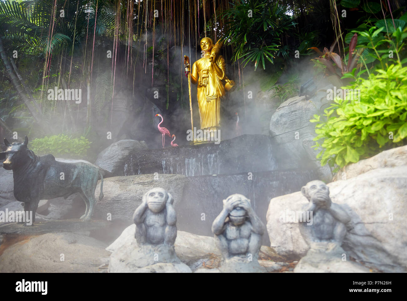 Goldene Buddha-Statue im tropischen Garten mit Wasserfall im Wat Saket goldenen Berg Tempel in Bangkok Stockfoto