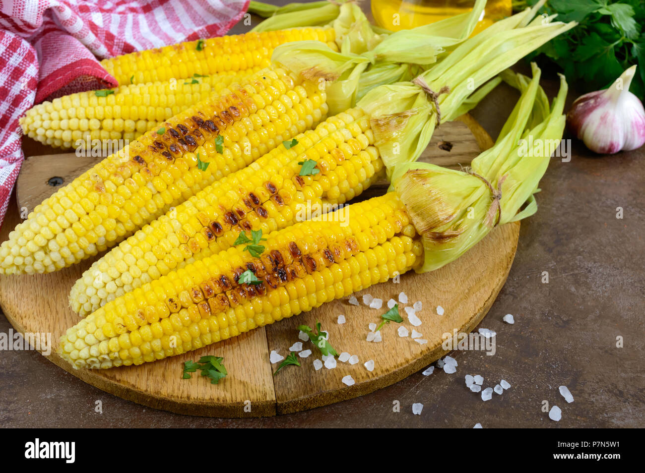 Frische leckere gegrillter Zuckermais mit Butter, Salz und Koriander auf einem Holztisch. Sommer oder Abendessen. Ideen für Grill Parteien. Veg Stockfoto