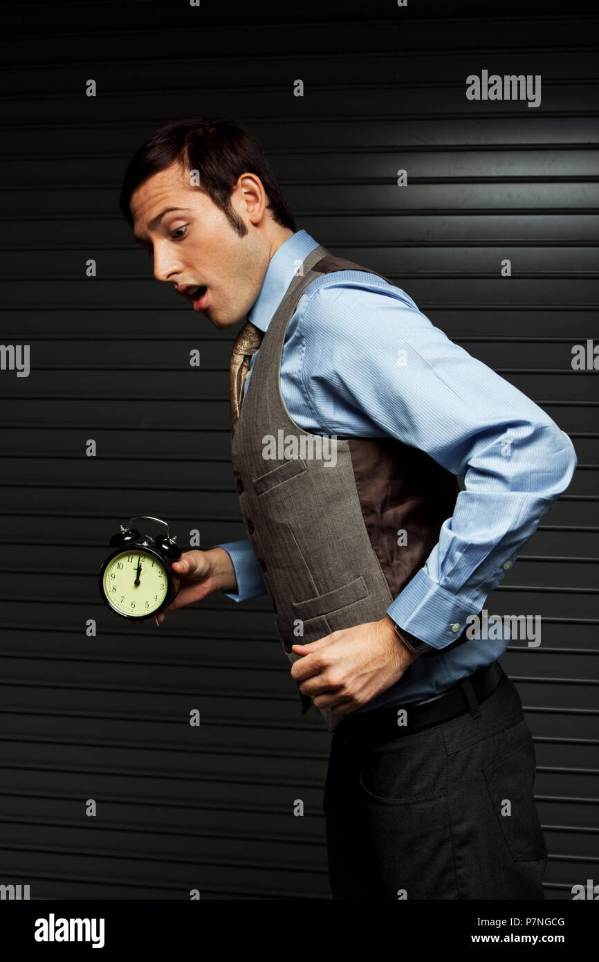 Gut gekleideter Mann hält eine Uhr. Stockfoto