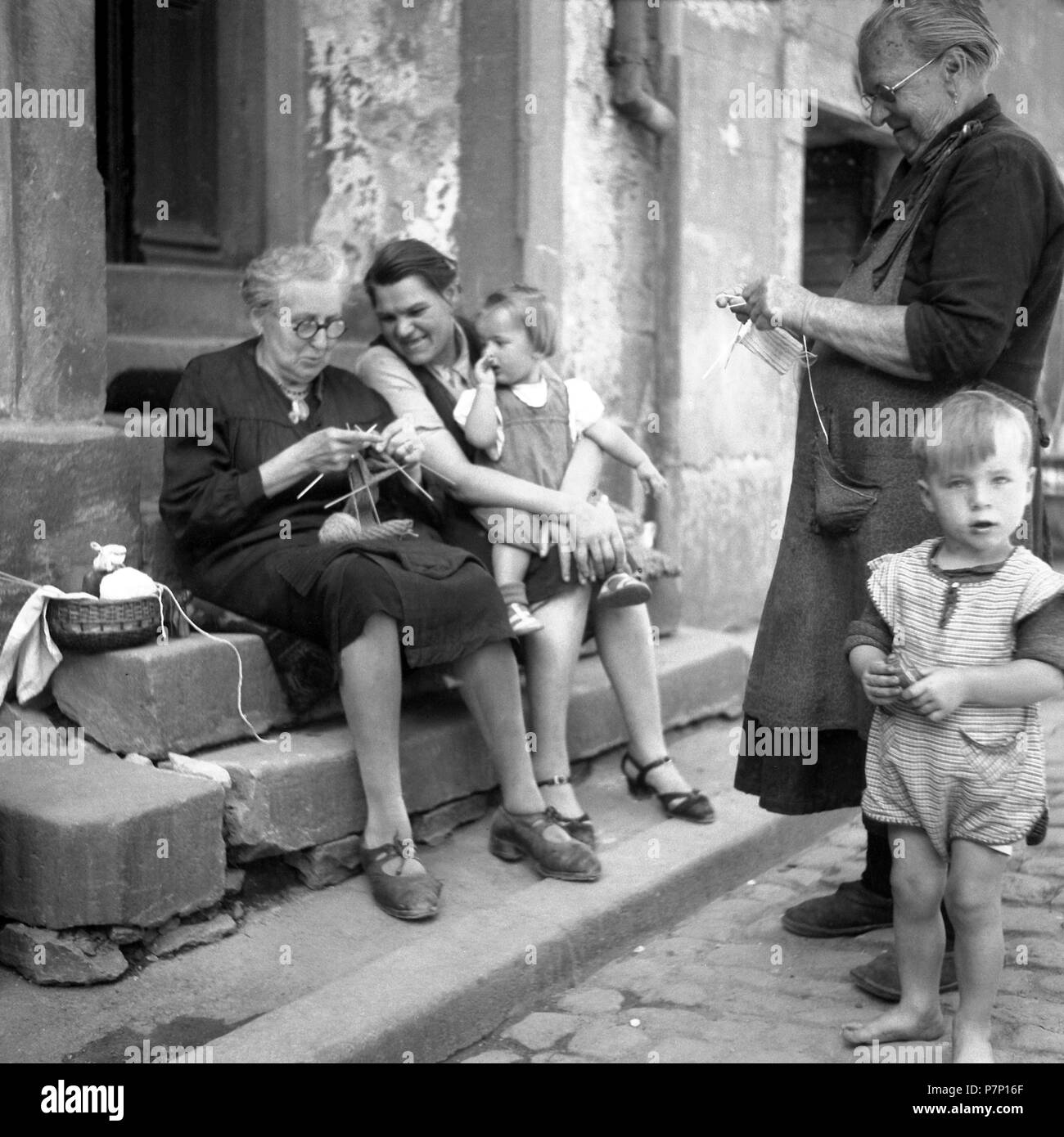 Mutter und Kinder scheuen, von den Großeltern, während Stricken, Stricken Familie am Straßenrand, Ca. 1950, in der Nähe von Freiburg Stockfoto