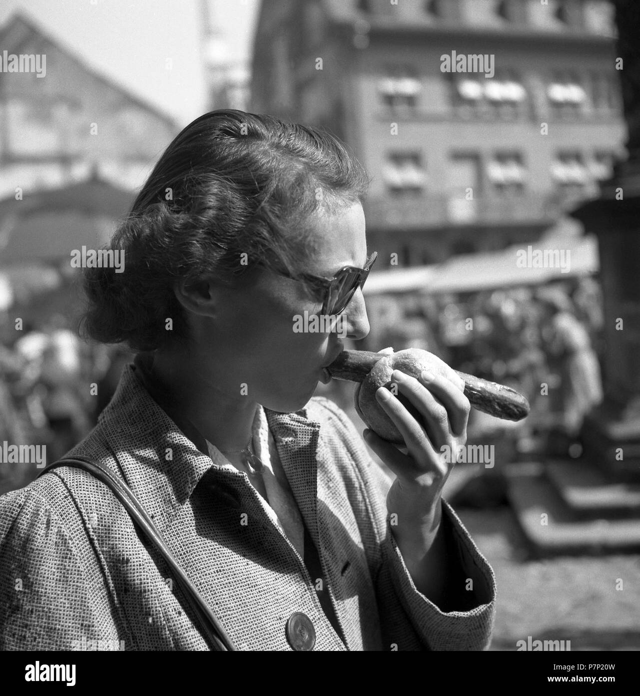 Frau isst Bratwurst im Brötchen auf dem Marktplatz, Freiburger Münstermarkt, ca. 1945 bis 1955, Freiburg, Deutschland Stockfoto