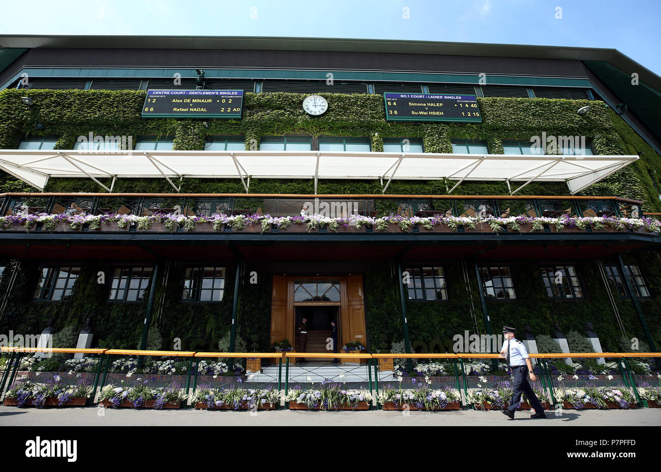 Ein Sicherheitsbeamter, als die Zeit um drei Uhr zuschlägt, als England am sechsten Tag der Wimbledon-Meisterschaften im All England Lawn Tennis and Croquet Club in Wimbledon sein Fußballweltmeisterspiel startet. Stockfoto