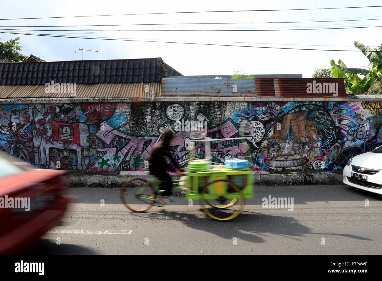 Jogjakarta, Indonesien - 22. Juni 2018: eine Rikscha Fahrer Fahrten Vergangenheit Graffiti und Verkehr auf Tirtodipuran Straße in Jogyakarta Stockfoto