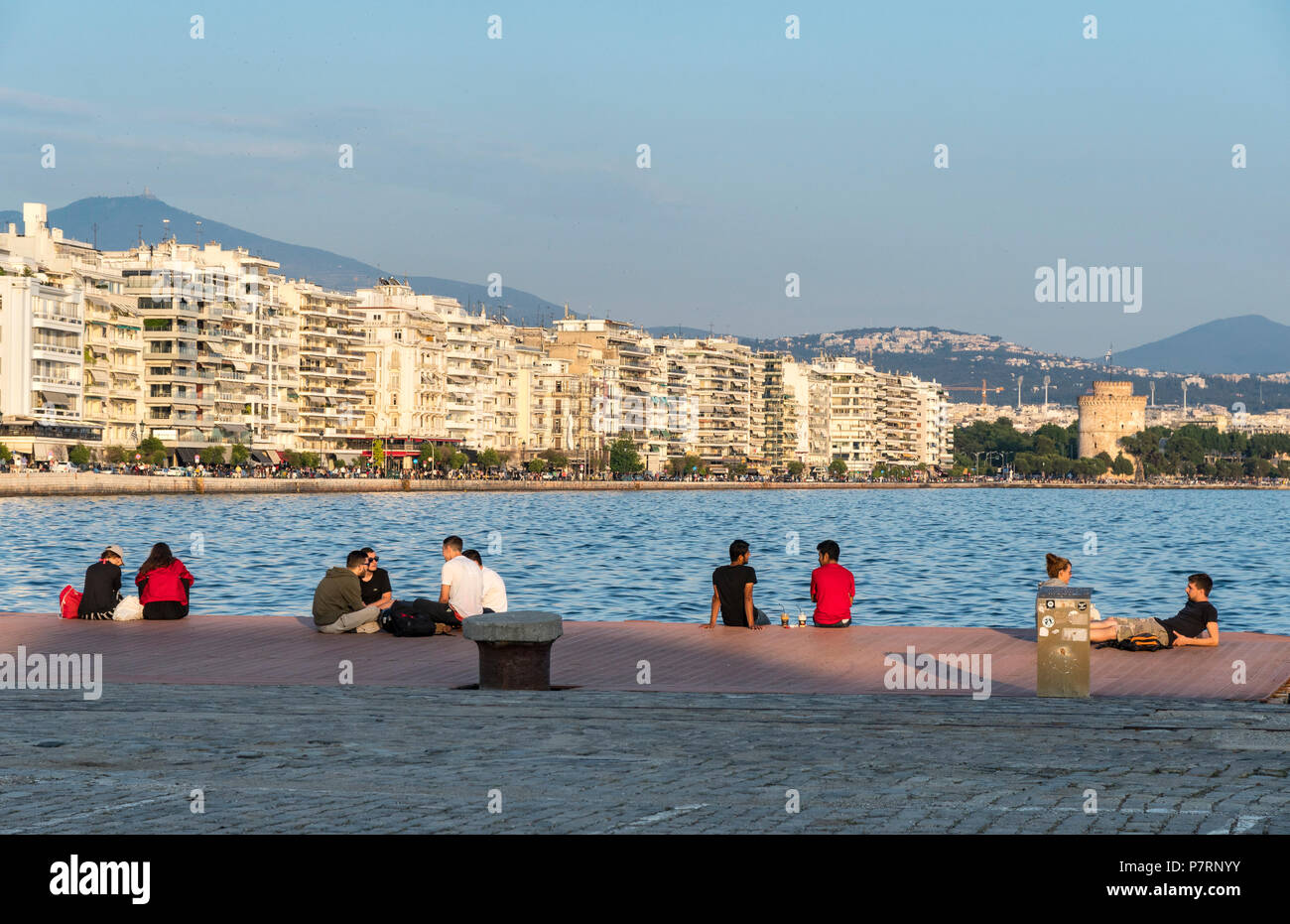 Menschen entspannend auf Thessaloniki Waterfront mit Apartment Blocks auf Nikis Avenue und den Weißen Turm im Hintergrund, Mazedonien, Nordgriechenland Stockfoto