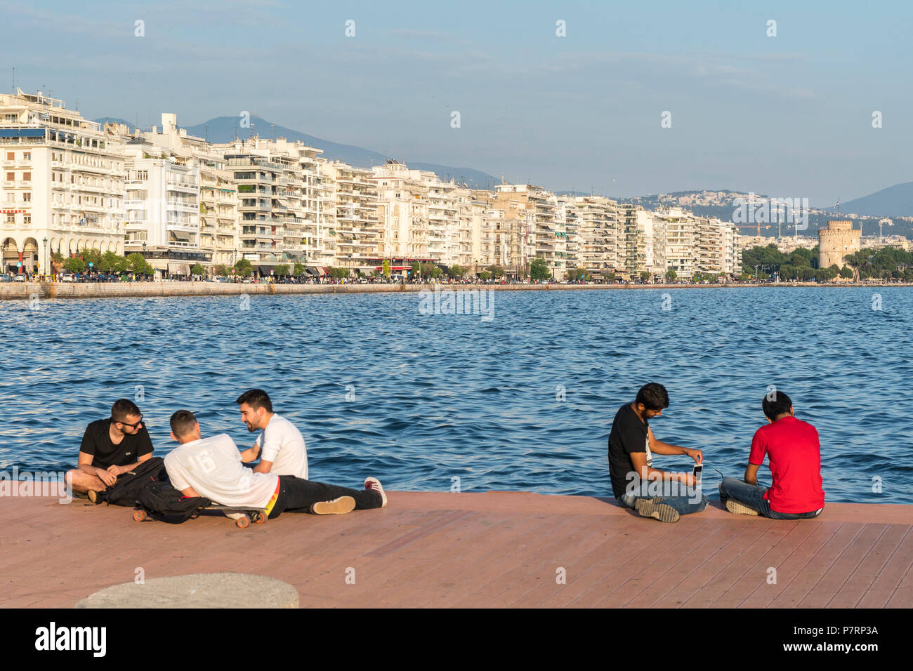 Menschen entspannend auf Thessaloniki Waterfront mit Apartment Blocks auf Nikis Avenue und den Weißen Turm im Hintergrund, Mazedonien, Nordgriechenland Stockfoto