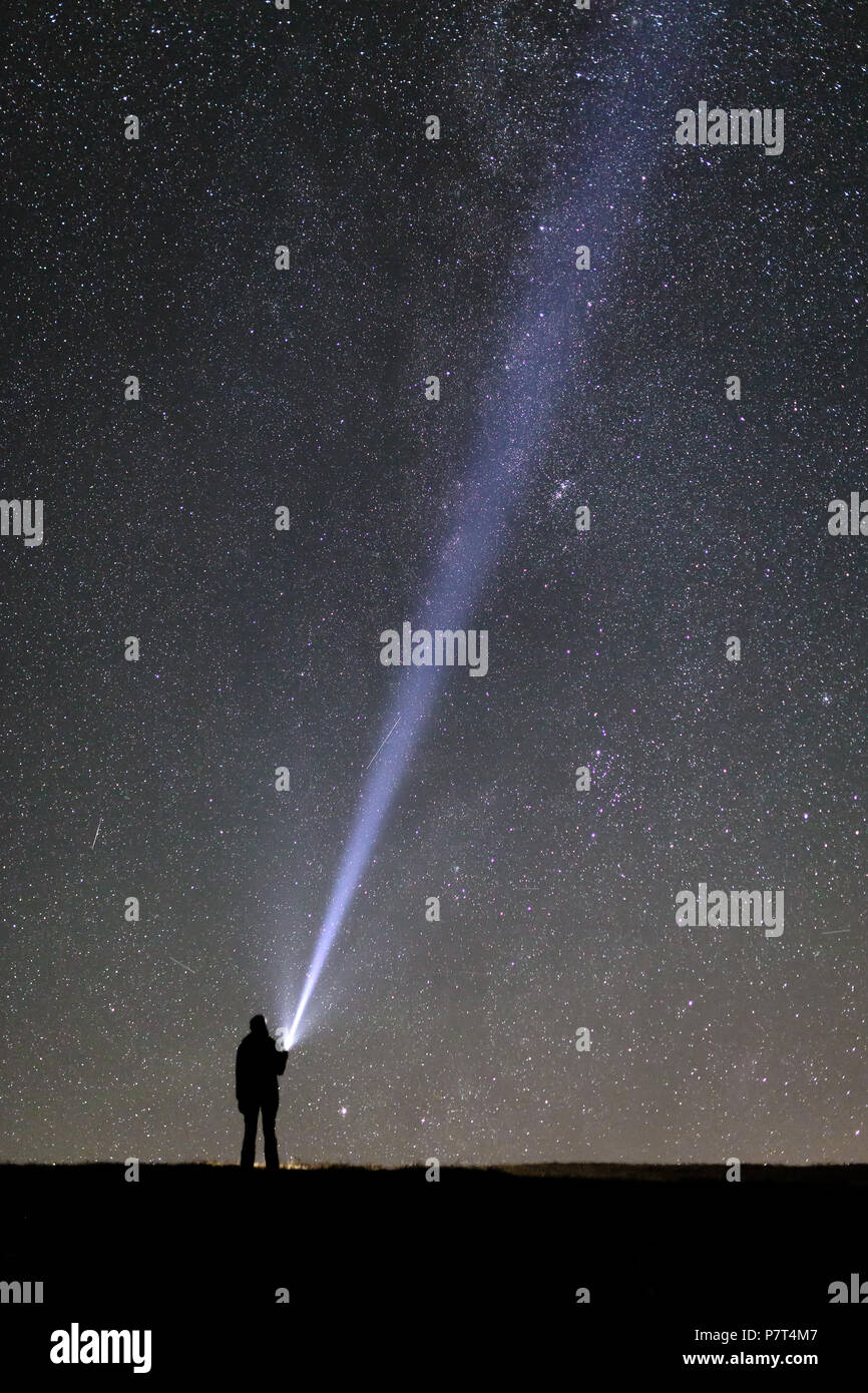 Silhouette einer Tourist mit einer Taschenlampe beobachten, schönen, weiten blauen Nachthimmel mit Sternen und Galaxien Stockfoto