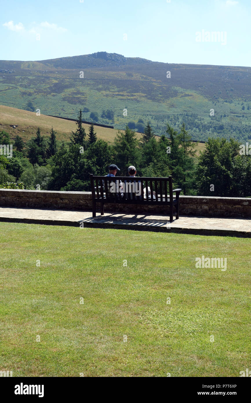 Ein Paar sitzt auf einer Holzbank an der Simon von Seat im Parcevall Hall Gardens, Skyreholme, Appletreewick, Wharfedale, Yorkshire, England, UK. Stockfoto