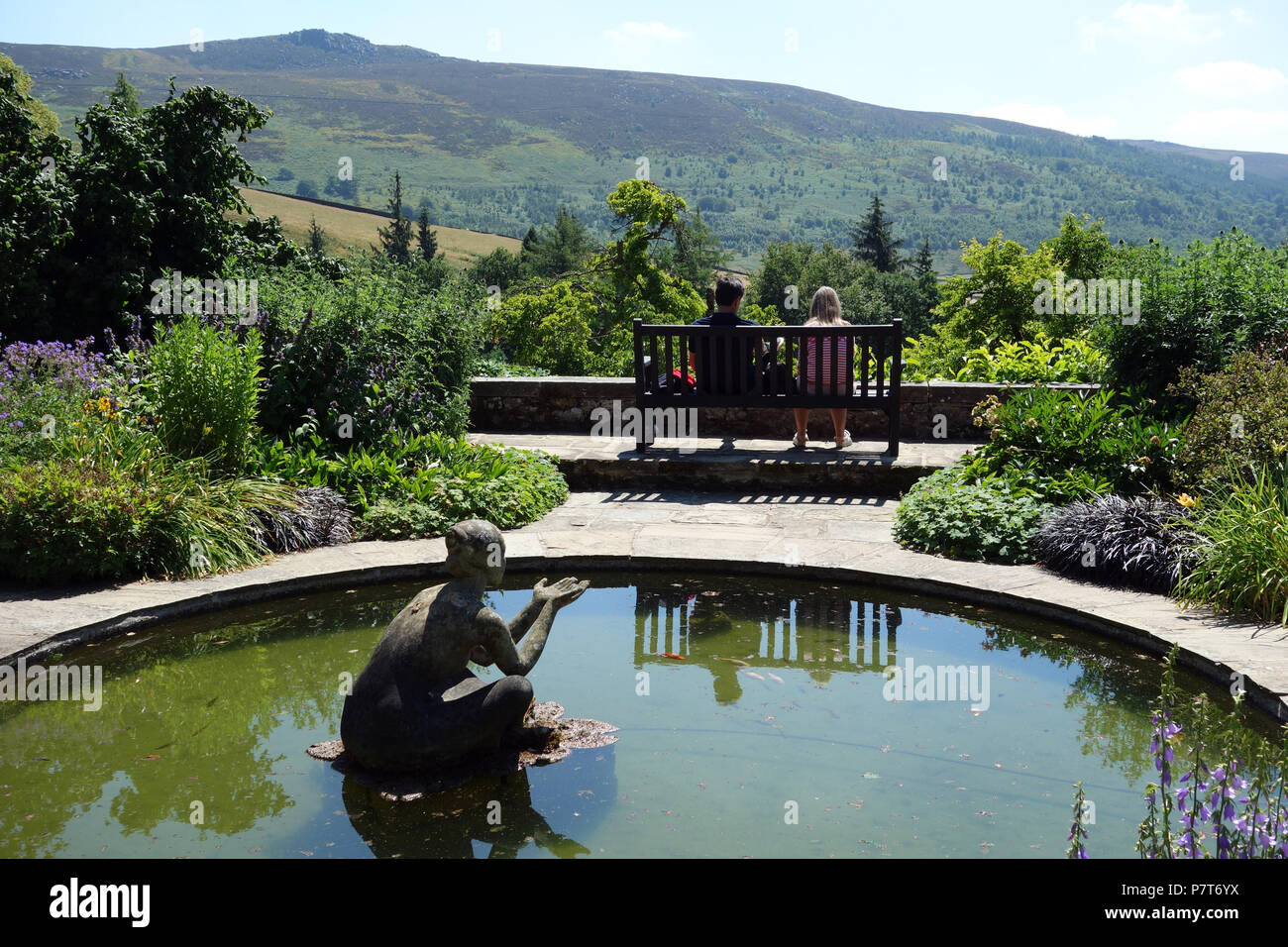 Ein Paar sitzt auf einer Holzbank an der Simon von Seat im Parcevall Hall Gardens, Skyreholme, Appletreewick, Wharfedale, Yorkshire, England, UK. Stockfoto
