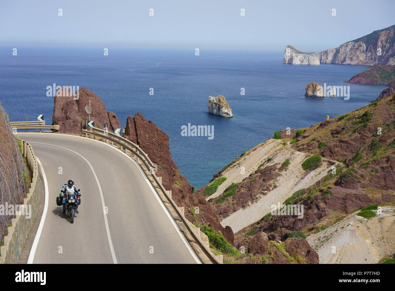 Fahrer auf einem Dual-Sport-Motorrad auf einer corniche mit Blick auf das Mittelmeer. Masua, Provinz Südsardinien, Sardinien, Italien. Stockfoto