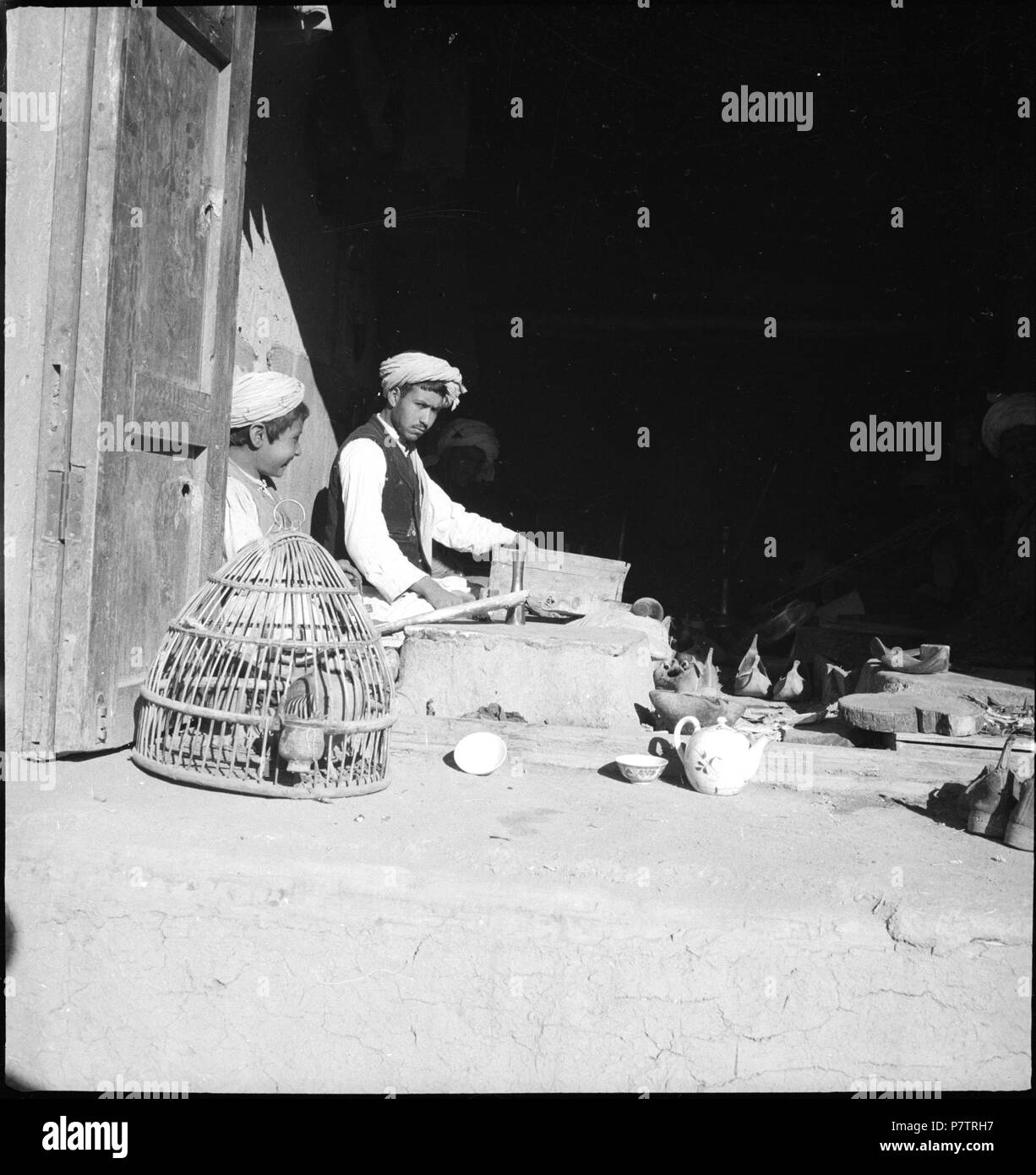 Afghanistan, Ghazni (ghaznah) Lehrwerk:; Männer mit einem Knaben sitzend in einem Haus, davor ein Vogelkäfig und Teegeschirr. Von 1939 bis 1940 64 CH-NB-Afghanistan, Ghazni (ghaznah) - Menschen - Annemarie Schwarzenbach - SLA-Schwarzenbach-A -5-21-165 Stockfoto