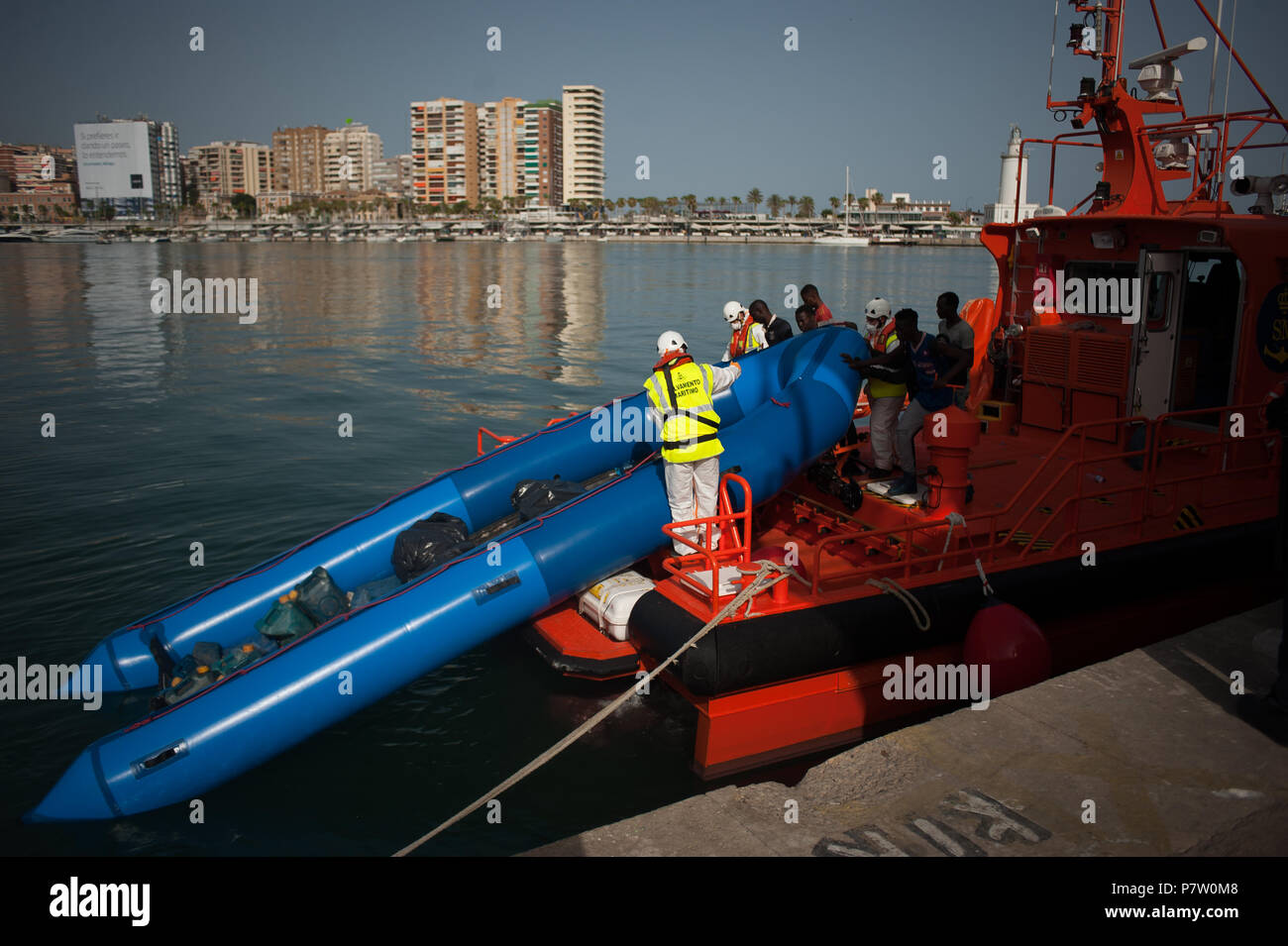 Malaga, Spanien. 7. Juli 2018. Migranten, drücken ihre Beiboot mit Rettungskräfte auf das Rettungsboot. Mitglieder der Spanischen Sicherheit auf See gerettet 56 subsaharische Migranten an Bord ein Beiboot in der Nähe der Küste von Malaga und brachte am Hafen von Malaga, wo sie durch das Spanische Rote Kreuz unterstützt wurden. Insgesamt wurden 80 Migranten gerettet dieser Samstag von Alboran See. Credit: SOPA Images Limited/Alamy leben Nachrichten Stockfoto