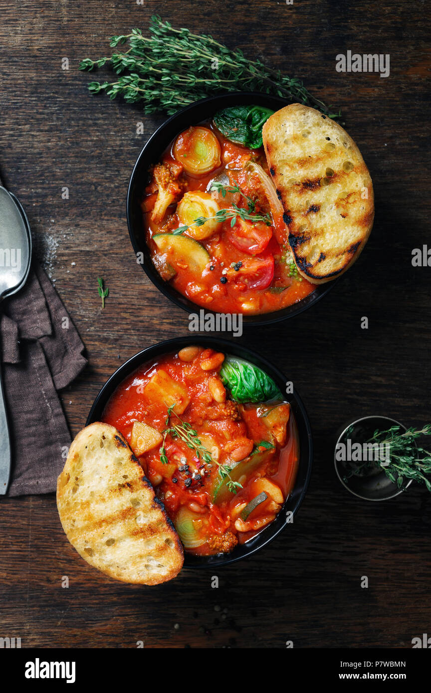 Italienische Suppe minestrone mit Gemüse der Saison auf einem dunklen Hintergrund, Ansicht von oben Stockfoto