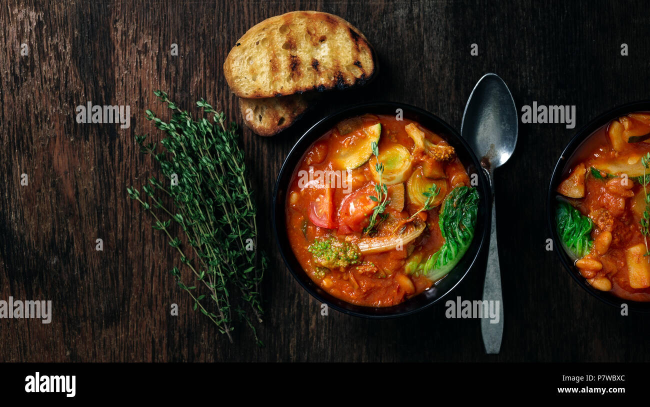 Italienische Suppe minestrone mit Gemüse der Saison auf einem dunklen Hintergrund, Ansicht von oben Stockfoto