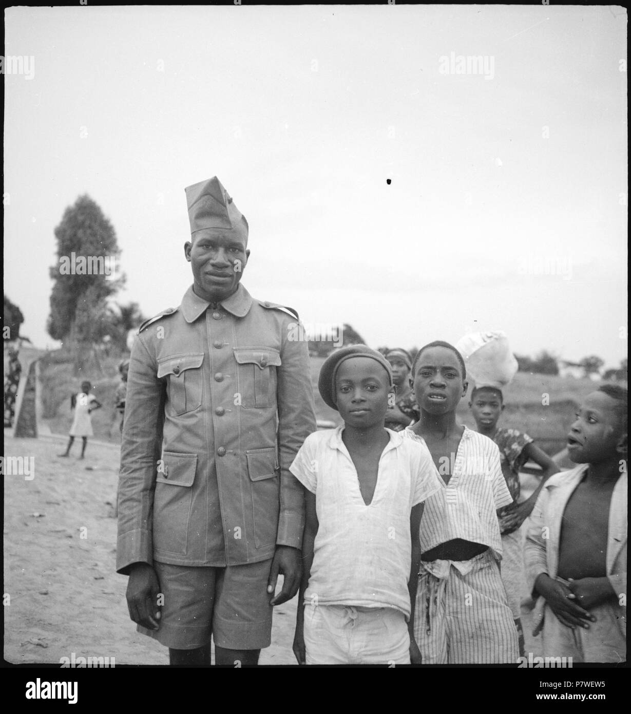 Belgisch-Kongo, Thysville (mbanza Ngungu) Lehrwerk:; Uniformierter Soldat zusammen mit mehreren Kindern im Stadtteil 'auf Belge' Einems unasphaltierten Weg holzbilderrahmen. von Mai 1941 bis März 1942 67 CH-NB-Belgisch-Kongo, Thysville (mbanza Ngungu) - Menschen - Annemarie Schwarzenbach - SLA-Schwarzenbach-A -5-26-067 Stockfoto