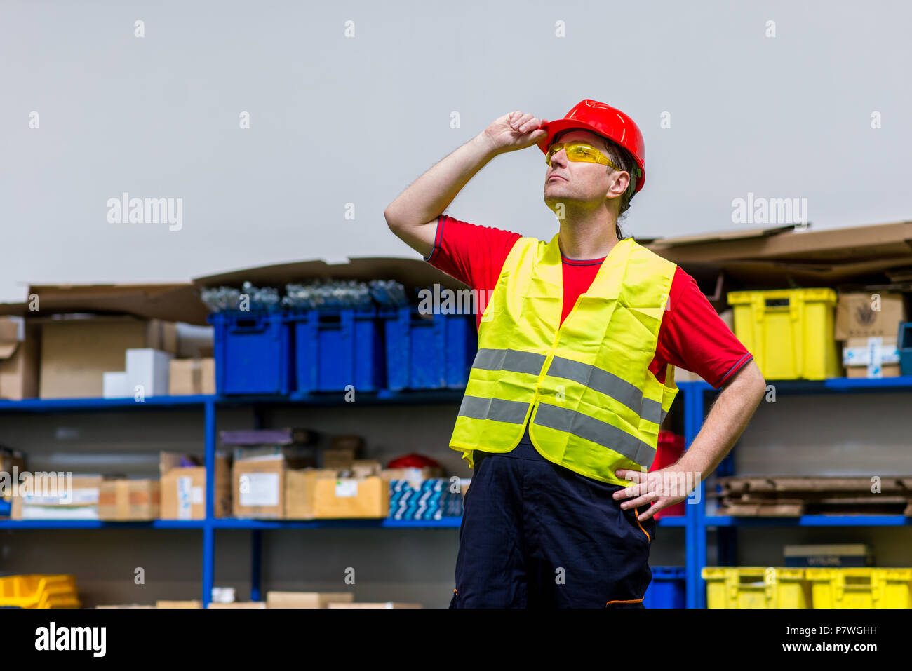 Arbeiter tragen gelbe reflektierende Westen, gelb Schutzbrille und Roten Helm. Arbeiter, die mit einer Hand auf seinem Helm Stockfoto