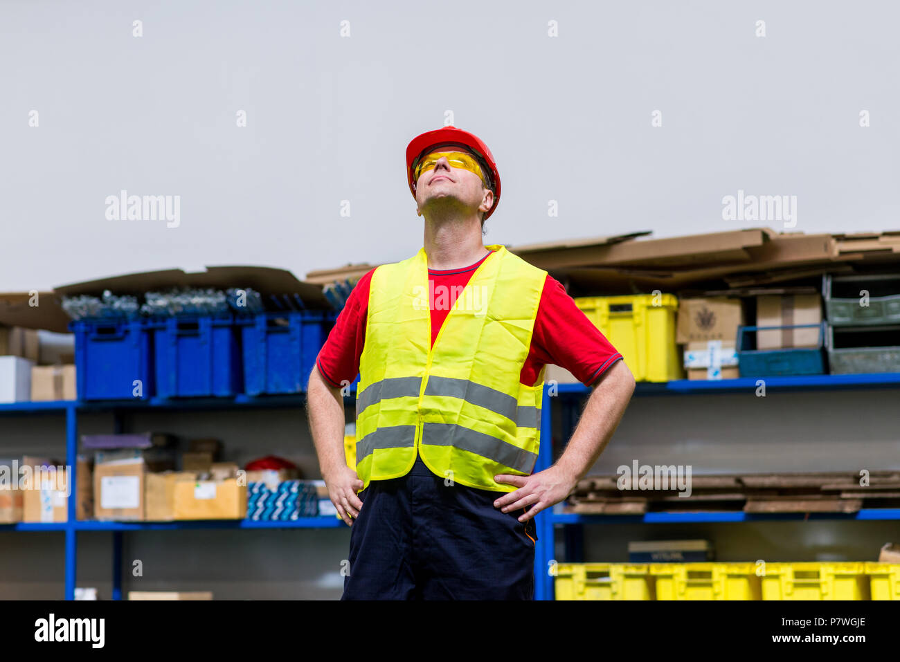Arbeiter tragen gelbe reflektierende Westen, gelb Schutzbrille und Roten Helm. Arbeiter mit den Händen auf den Hüften suchen Stockfoto