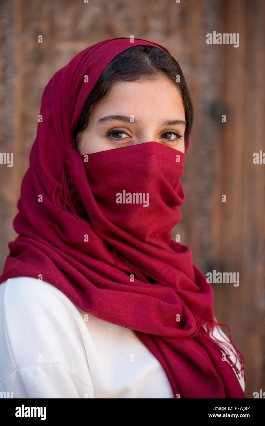 Portrait von jungen muslimischen Frau mit roten hijab Kopftuch über ihr Gesicht Stockfoto