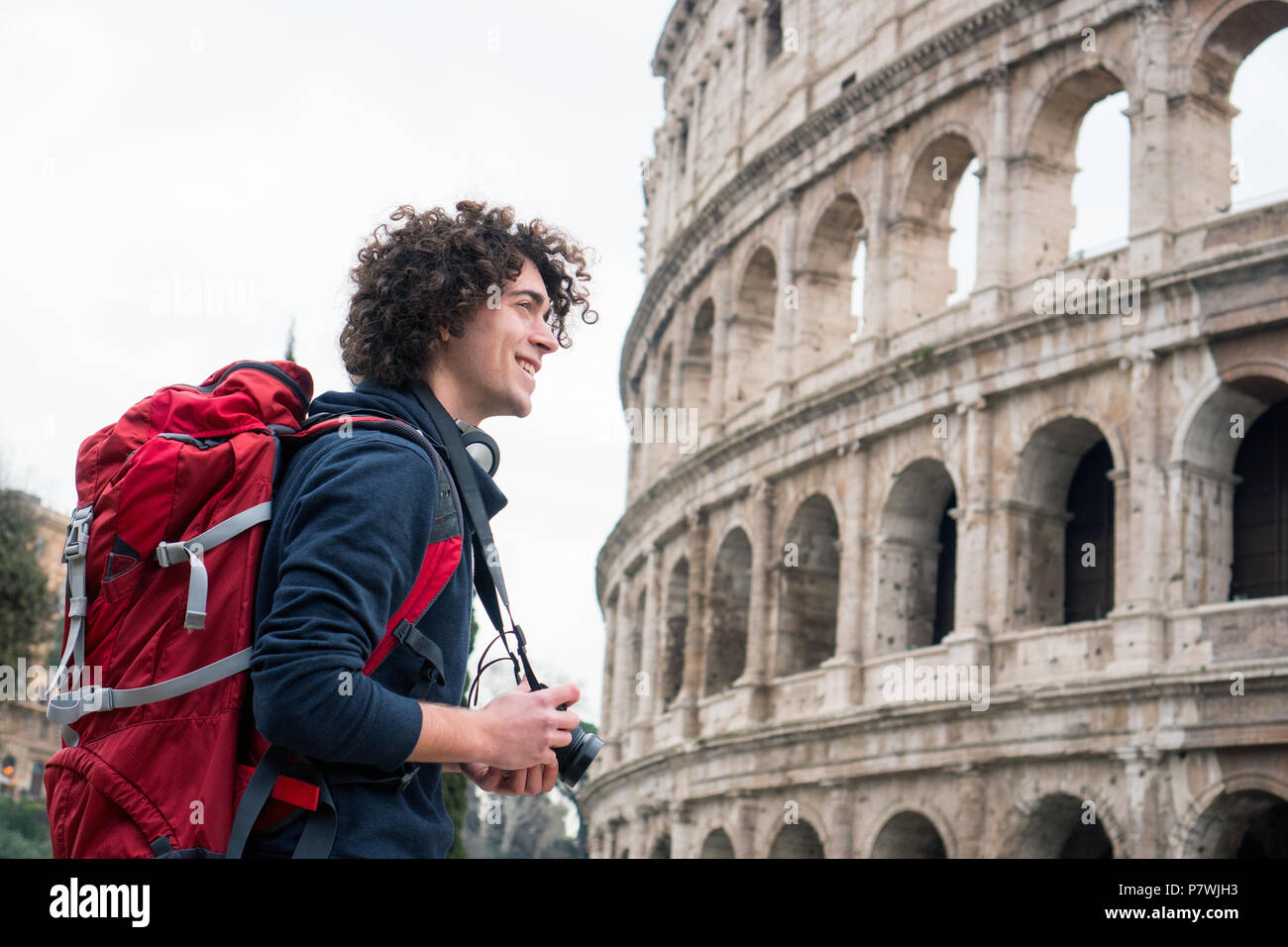Hübscher junger Tourist Mann mit Kamera und Rucksack, die Bilder von Kolosseum in Rom, Italien. Jungen Touristen, die Bilder von Kolosseum Stockfoto