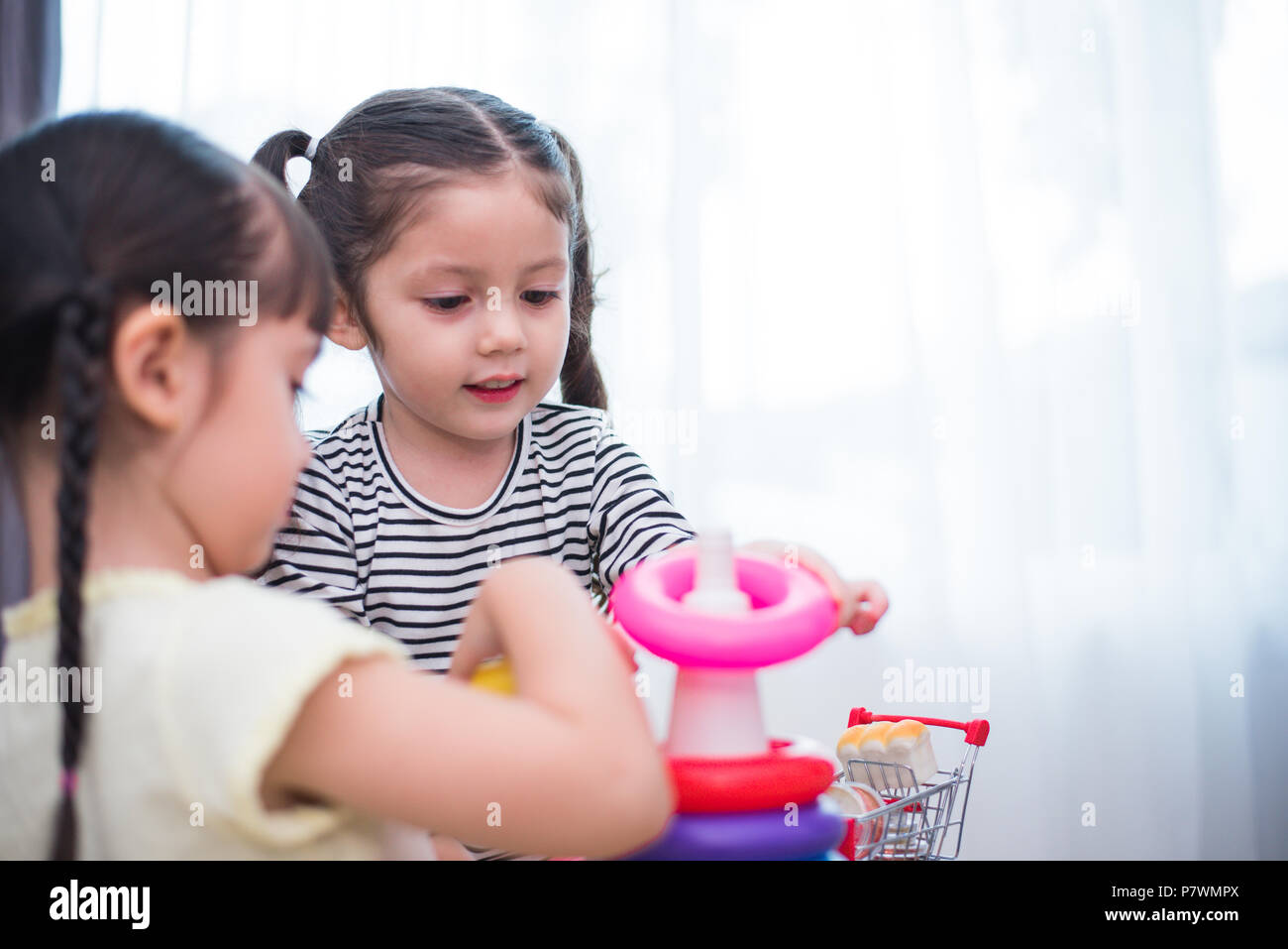 Zwei kleine nette Mädchen spielen Spielzeug Bänder in Haus Kleine Mädchen spielen kleines Spielzeug Bänder in Home