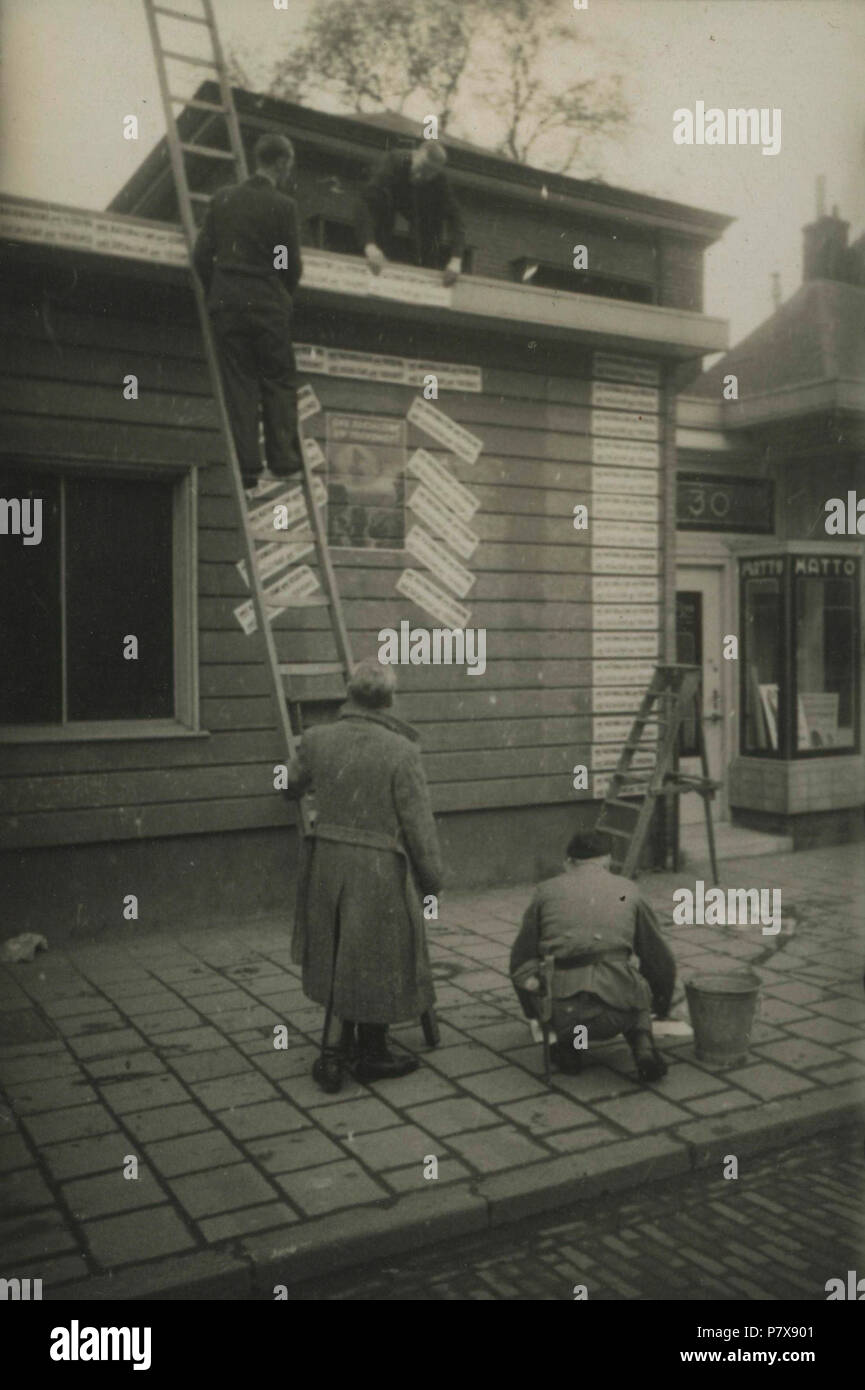 . De strijd om Amsterdam. Nederlands: NSB-registrierte, waaronder een ouder Lid van de Jeugdstorm, gebouwtje beplakken een met leuzen. Waarschijnlijk de leus: "Ons nationalisme uw Redding, ons Socialisme uw Toekomst', Sterben werd gebruikt tijdens De Drie maanden durende actie: "Strijd om Amsterdam "van 04-03-1944 Tot en Met 15 -06-1944. Deze foto ist afkomstig uit het Archief van de Fotodienst der NSB. 30. April 1944 129 De strijd om Amsterdam - Fotodienst der NSB-Niod-211841 Stockfoto