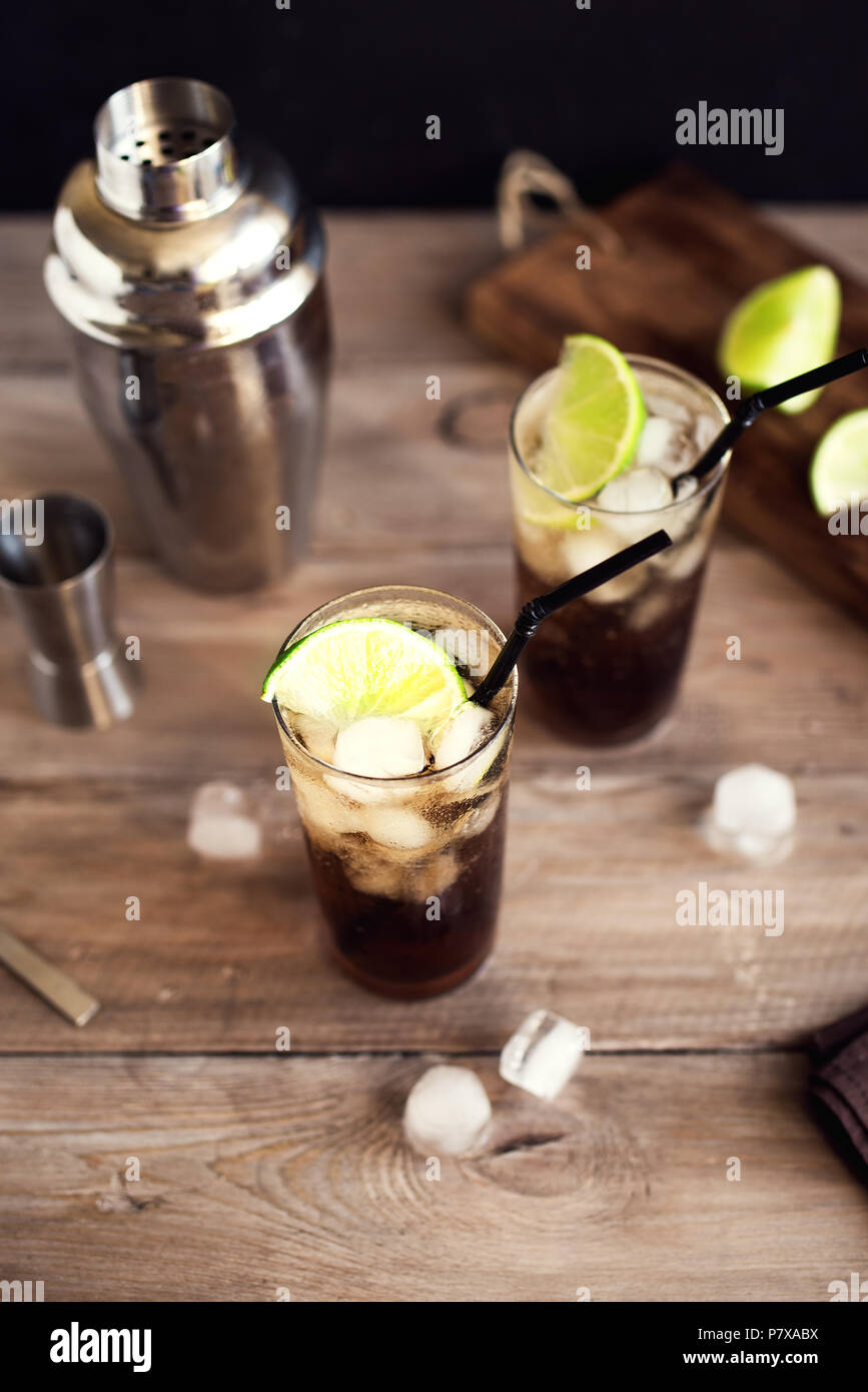 Rum und Cola Cuba Libre trinken mit Kalk und Eis auf rustikalen Holztisch Stockfoto