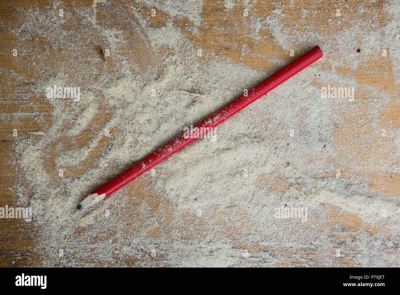 Verwendet der Bau oder die industrielle Holz- rot Graphit Bleistift auf hölzernen Schreibtisch mit Sägemehl Stockfoto