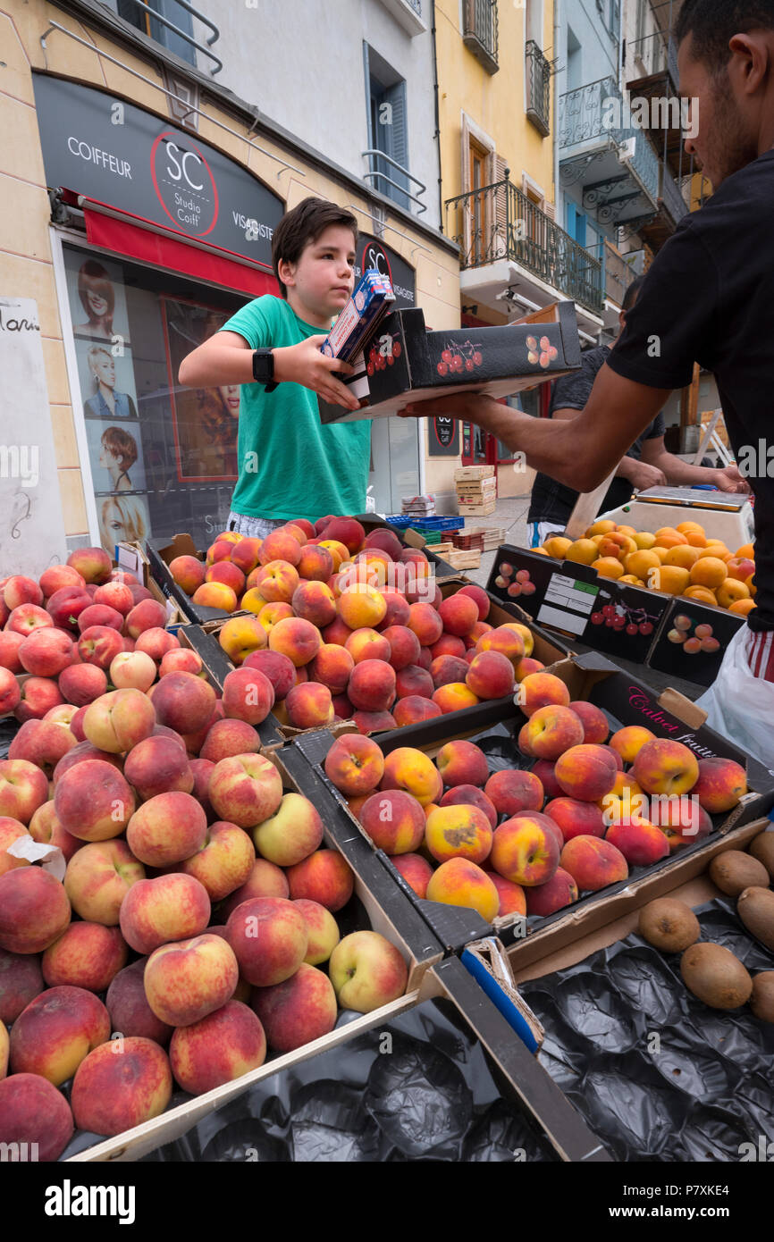 Junge verkauft Pfirsiche und anderen Früchten auf Open-air-Markt von briancon in der französischen Haute Provence Stockfoto