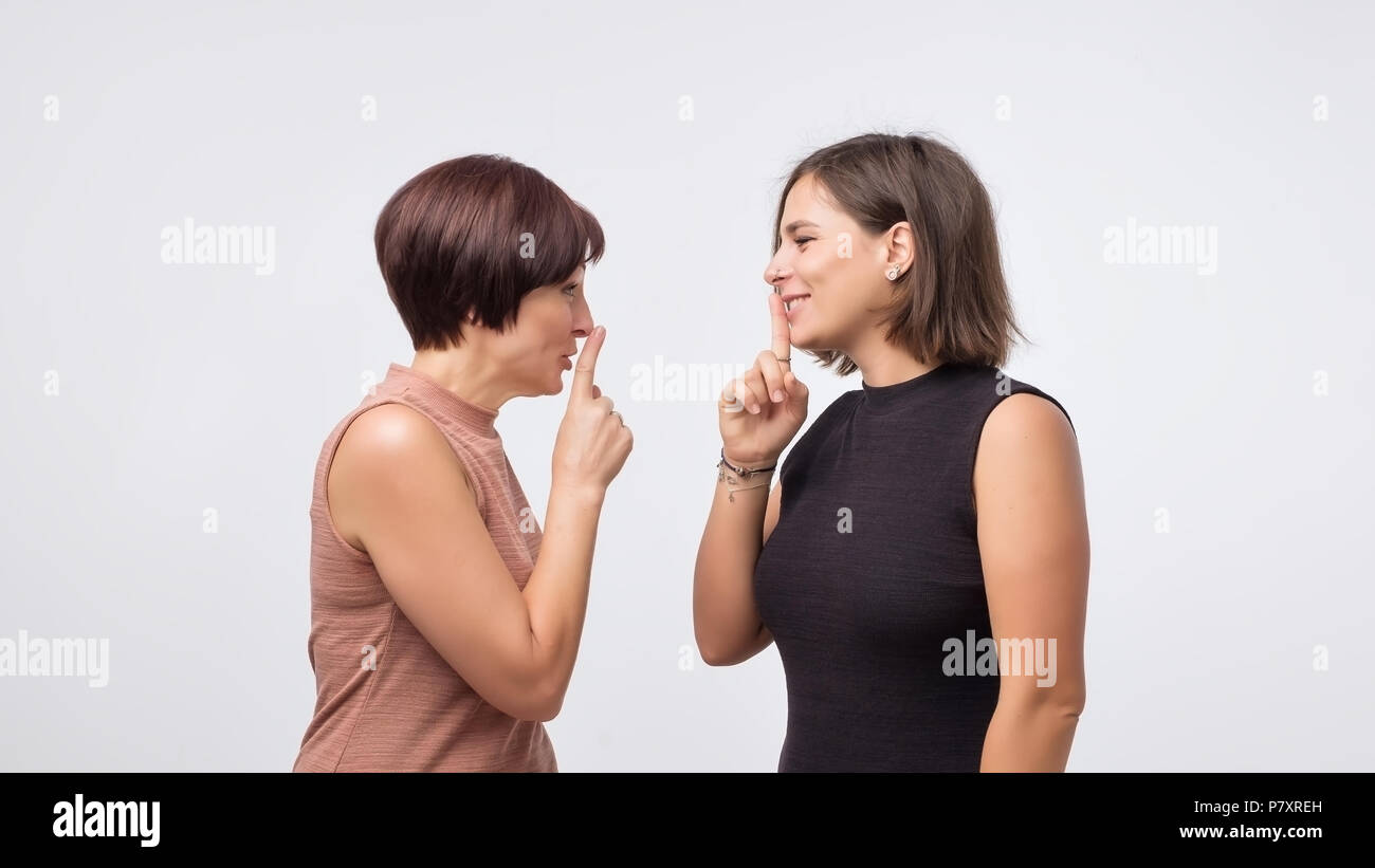 Frauen Mutter und Tochter klatschen und sagen ein Geheimnis über grauer Hintergrund isoliert. Stockfoto