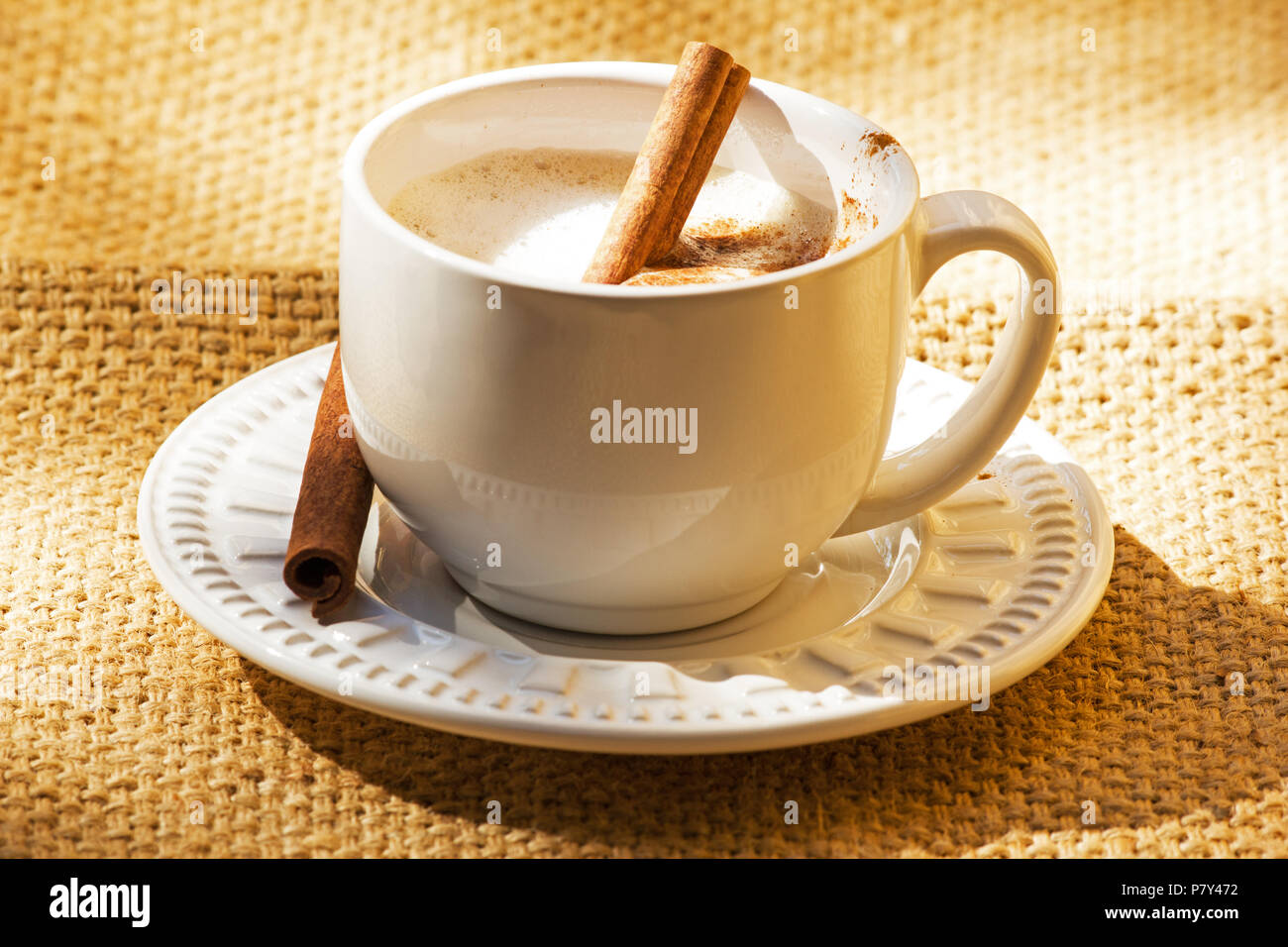Tasse Kaffee mit Zimtstangen auf sackleinen Stockfoto