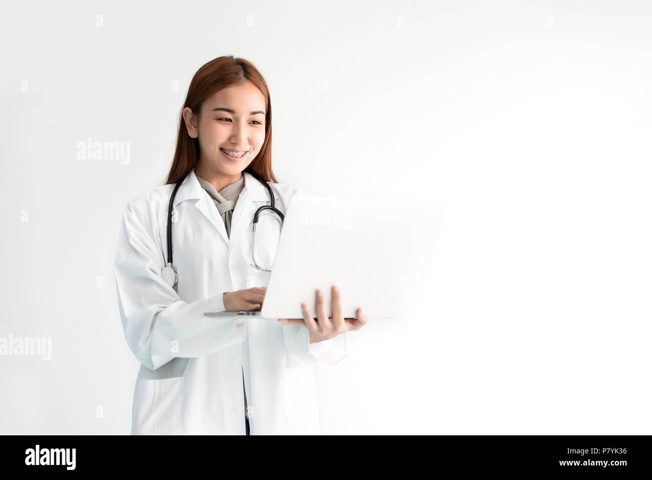 Ärztin mit Laptop mit Stethoskop auf weißem Hintergrund. Ärzte und medizinisches Konzept. Mensch und Technik Thema Stockfoto