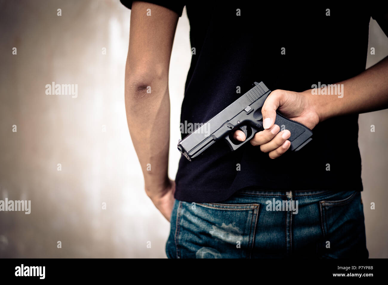 Räuber Pistole in den Rücken verstecken. Kriminelle und Mord Konzept. Die Verarbeitung und split Ton pinterest und instragram wie Process. Ansicht von hinten Stockfoto