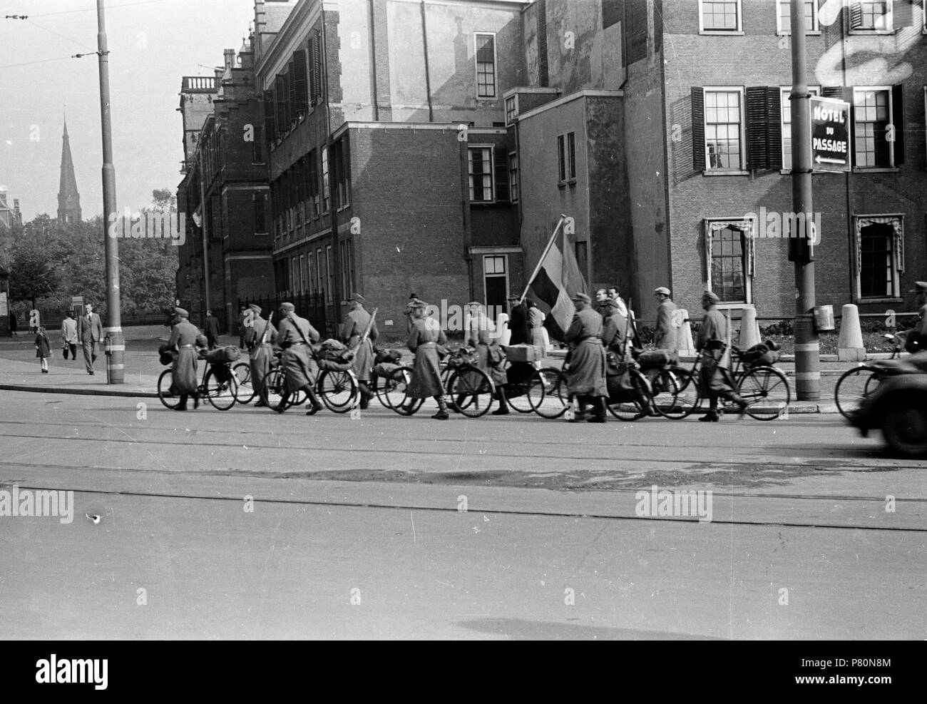 . Huizinga collectie Duitse overgave - Niod-217064. Nederlands: Foto uit de collectie Huizinga van het NIOD. Duitse militairen Lopen, na Hun overgave, met een fiets aan de Hand langs een Mann met een Nederlandse vlag richting Germany. Menno Huizinga war onderdeel van de Ondergedoken Kamera en-de illegaal maakte Foto tijdens bezetting. Dit tat hij zijn woonplaats hoofdzakelijk in Den Haag. Datum unbekannt 39 BC856 HUI-1941 Stockfoto