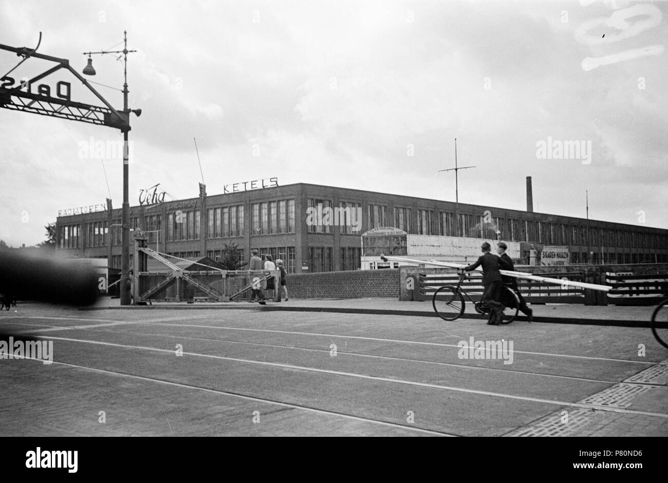 . Huizinga collectie vlaggenstokken - Niod-217075. Nederlands: Foto uit de collectie Huizinga van het NIOD. Twee Mannen vervoeren Twee vlaggenstokken über een stadsbrug. Menno Huizinga war onderdeel van de Ondergedoken Kamera en-de illegaal maakte Foto tijdens bezetting. Dit tat hij zijn woonplaats hoofdzakelijk in Den Haag. Datum unbekannt 40 BC856 HUI-1849 Stockfoto