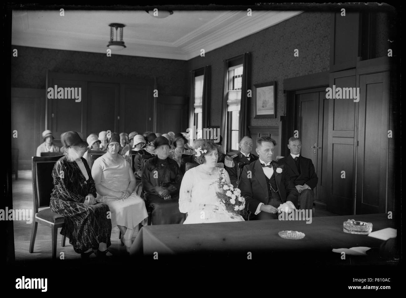 Gemeentehuis trouwzaal met bruidspaar en Gasten tijdens burgerlijk huwelijk Den Helder 1930 Catalogusnummer: RAA 003012609 Collectie Regionaal Archief Alkmaar. 12 Oktober 2011, 18:04 169 Gemeentehuis (31077639121) Stockfoto
