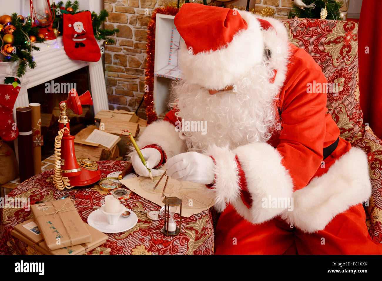 Santa Claus zu Hause suchen Karte und Pläne, um den Planeten zu reisen. Der Weihnachtszeit. Zeit für Wunder. Stockfoto