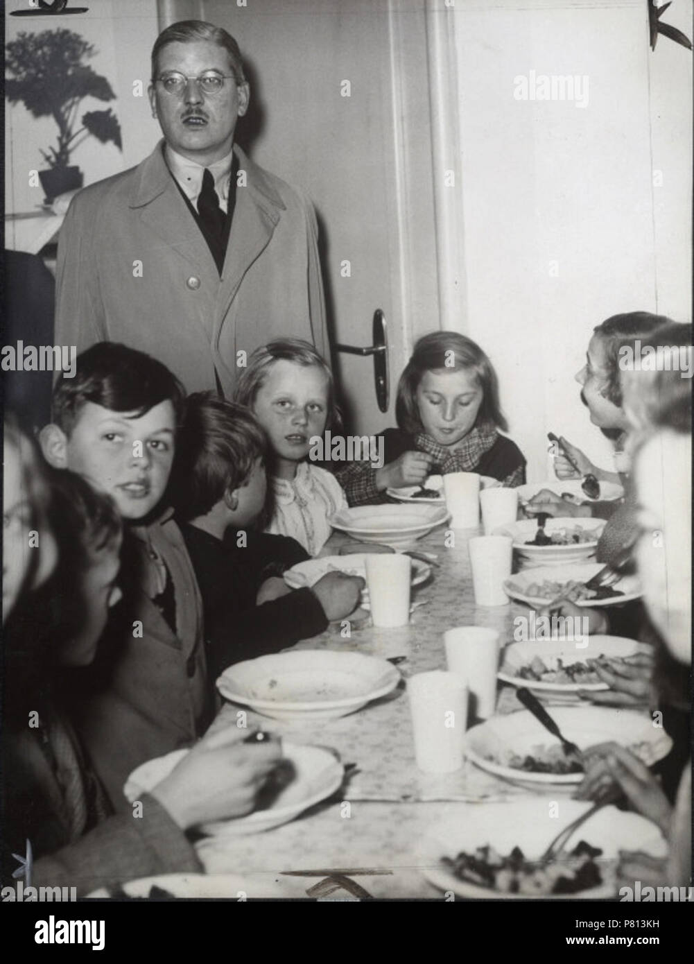 English: Bildnis (: Halbfigur Holzbilderrahmen, en face) in der Gruppe mit essenden Kindern bei einem 206 eines Mittagstisches im Rahmen des Hilfswerkes "Nehmt hungernde Kinder zum Mittagstisch.". 10 April 1937 343 SchuschniggVisitaUnComedorDeCaridad 19370410 Stockfoto
