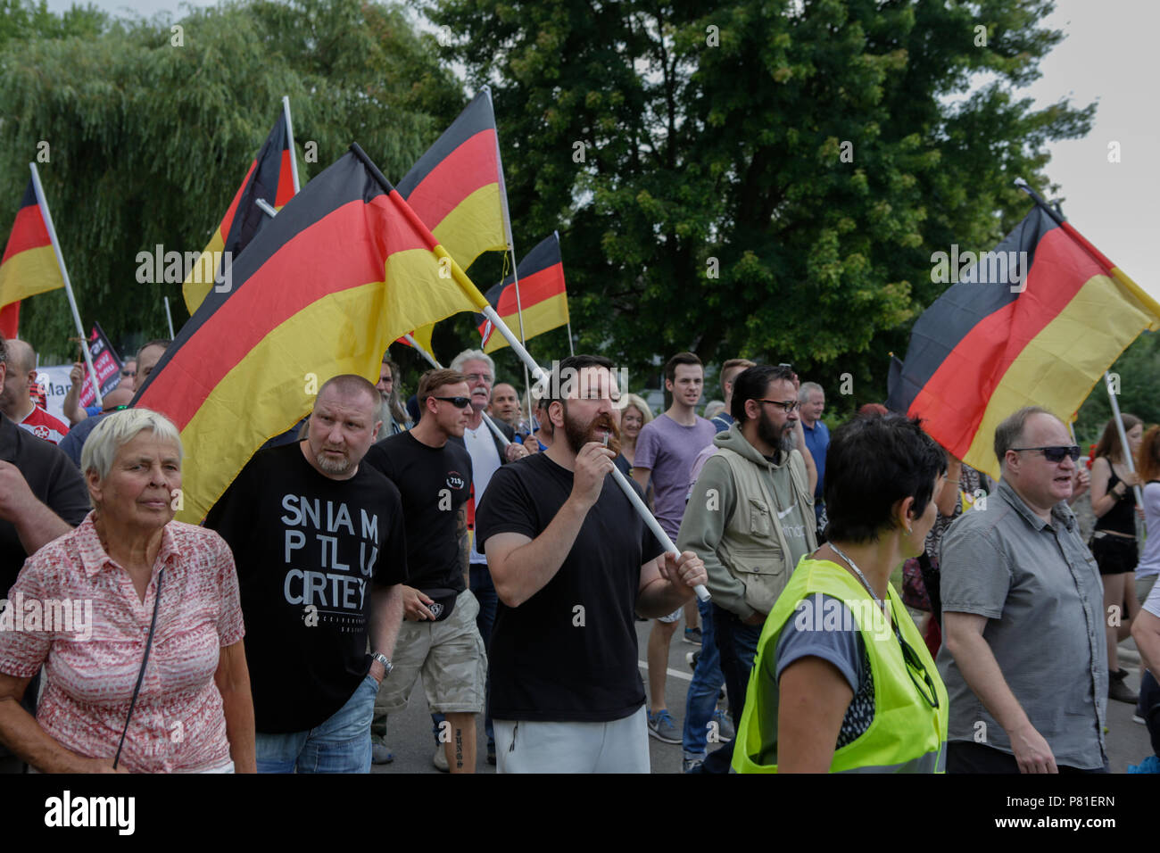 Kandel, Deutschland. 07 Juli, 2018. Die rechten Demonstranten März durch Kandel mit deutschen Fahnen. Rund 200 Menschen von Rechten Organisationen protestierten für das 10. mal in der Stadt Kandel in der Pfalz gegen Flüchtlinge, Ausländer und der deutschen Regierung. Sie forderten mehr Sicherheit von Deutschen und Frauen aus der angeblichen Zunahme der Gewalt durch Flüchtlinge. An die Stelle der Protest wurde gewählt, weil der 2017 Kandel erstechen Angriff, bei dem ein 15 Jahre altes Mädchen von einem Asylbewerber getötet wurde. Sie wurden von rund 200 anti-faschistischen counter-Demonstranten aus unterschiedlichen politischen Teil belästigt Stockfoto