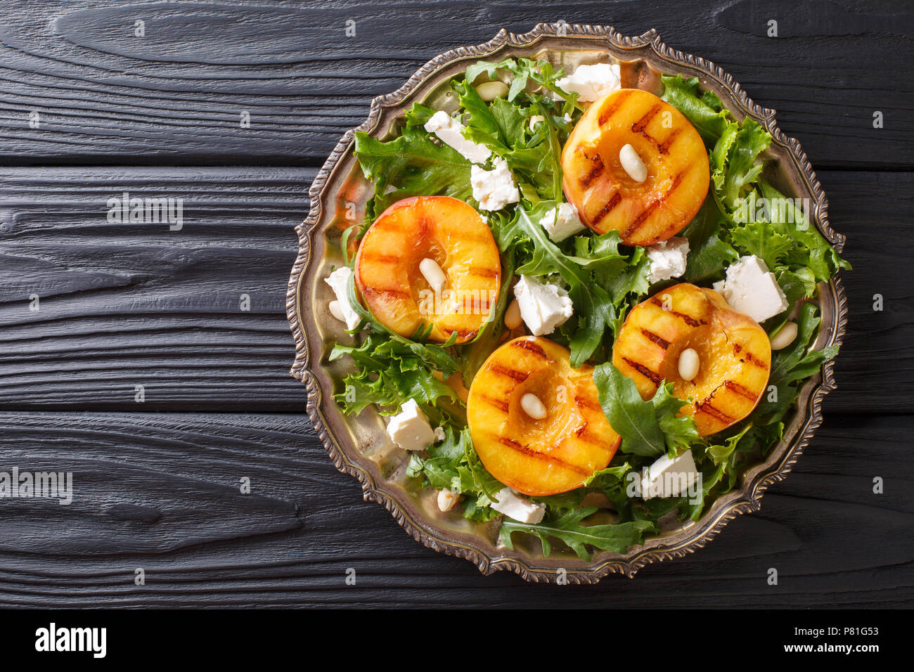 Vegetarische Ernährung Salat mit gegrilltem Pfirsiche, mit Schafskäse, Rucola, Erdnüsse und Kräuter close-up auf einem Teller auf dem Tisch. horizontal oben Ansicht aus einem Stockfoto