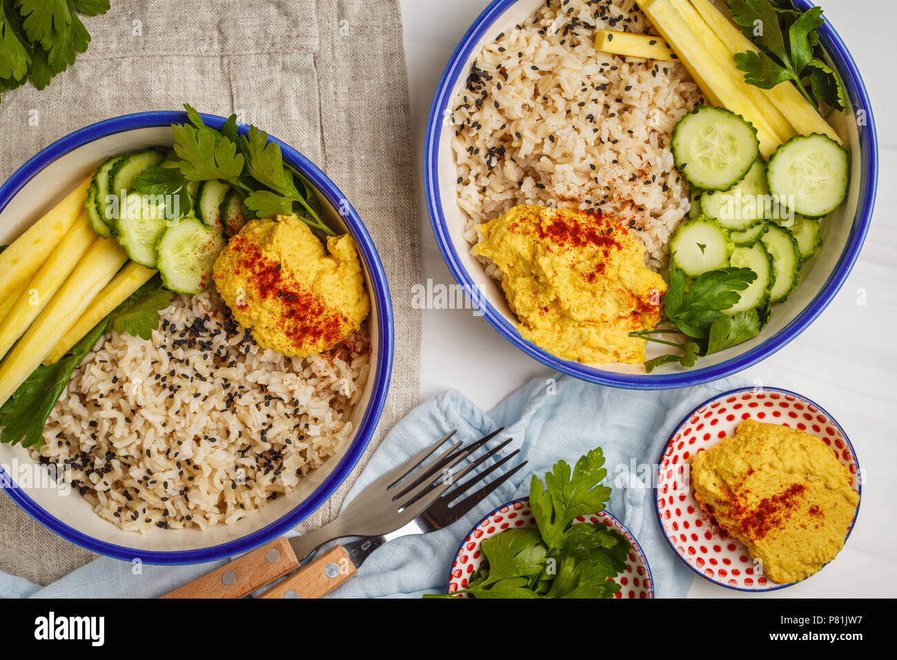 Veganes Mittagessen mit Reis, Hummus und Gemüse in weißen Platten, Ansicht von oben. Gesunde vegetarische Essen Konzept. Stockfoto