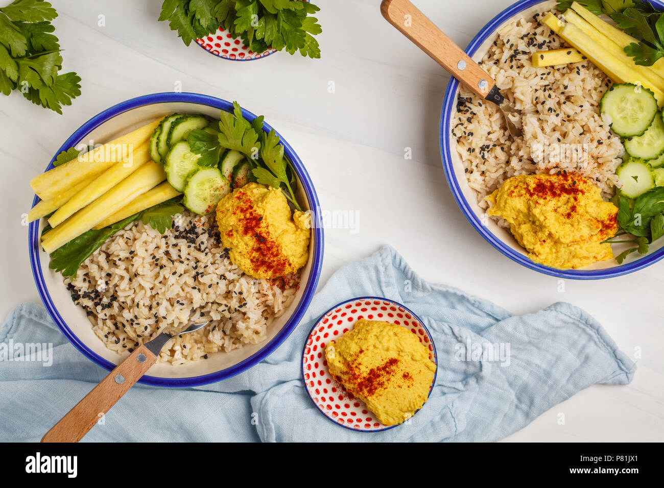 Veganes Mittagessen mit Reis, Hummus und Gemüse in weißen Platten, Ansicht von oben. Gesunde vegetarische Essen Konzept. Stockfoto