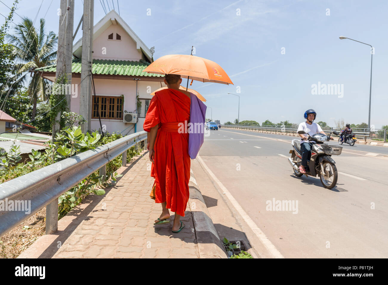 Mönch mit Regenschirm für Schatten auf dem Bürgersteig, Pakse, Laos Stockfoto
