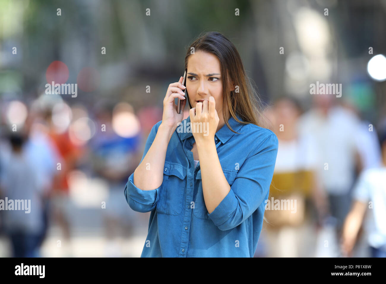 Nervöse Frau Beißen Nägel während ist am Telefon sprechen auf der Straße Stockfoto