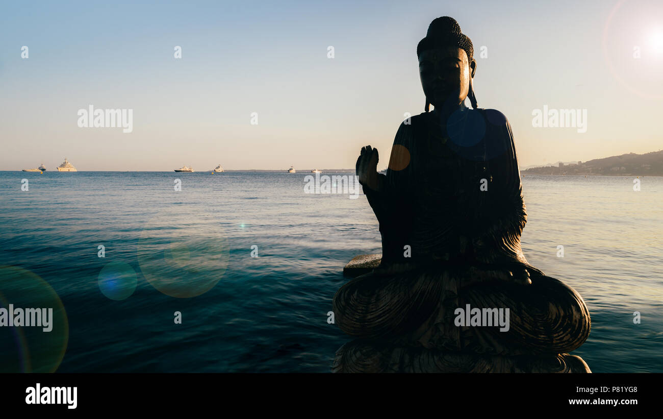Teilweise Silhouette aus Holz Buddha in Wasser mit Sonne Flares. Konzepte des Zen, Gleichgewicht, Ruhe, Spiritualität und Frieden Stockfoto