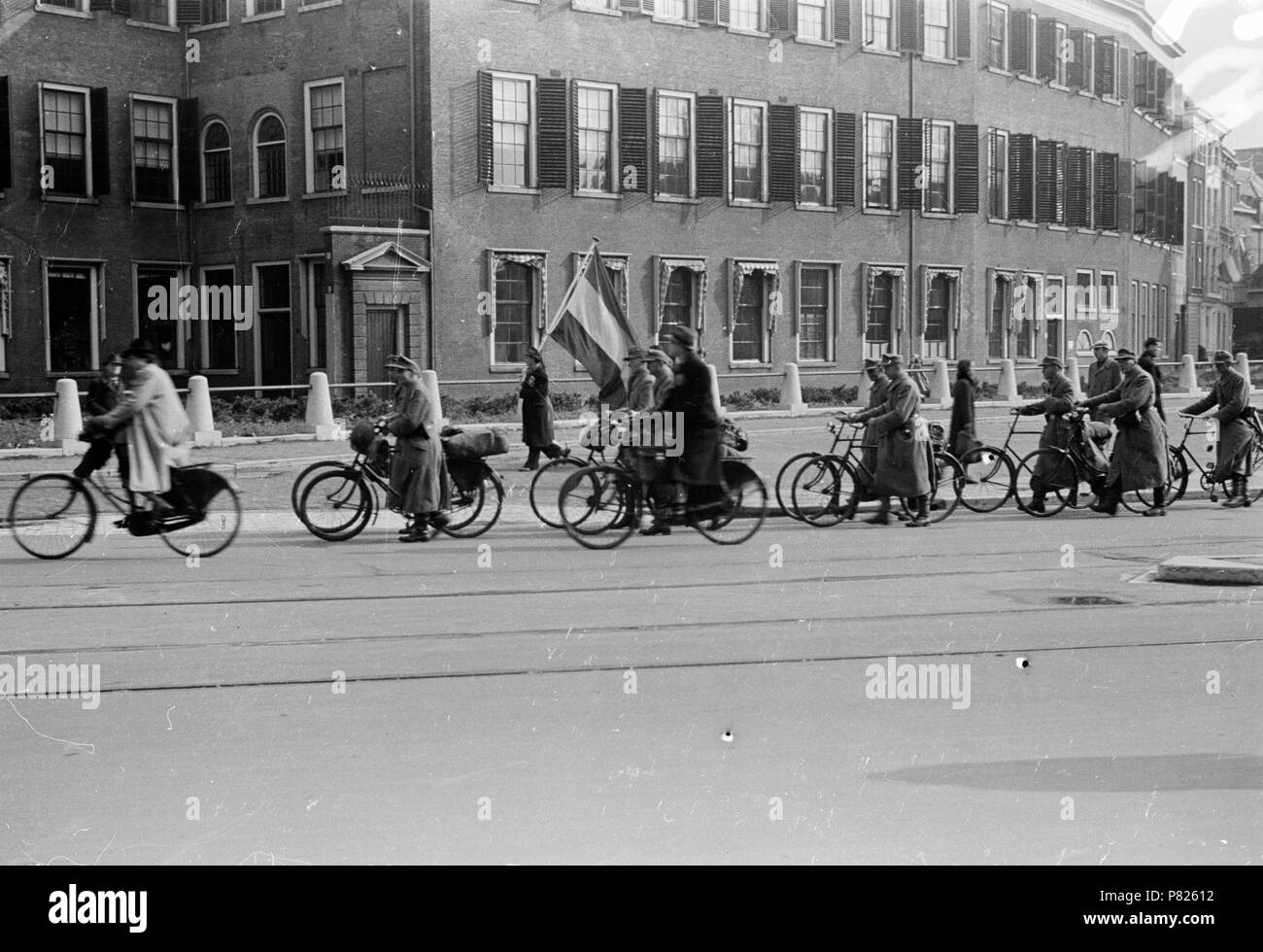 . Huizinga collectie Duitse overgave - Niod-217065. Nederlands: Foto uit de collectie Huizinga van het NIOD. Duitse militairen Lopen, na Hun overgave, met een fiets aan de Hand langs Mensch een met Nederlandse vlag. Menno Huizinga war onderdeel van de Ondergedoken Kamera en-de illegaal maakte Foto tijdens bezetting. Dit tat hij zijn woonplaats hoofdzakelijk in Den Haag. Datum unbekannt 39 BC856 HUI-1838 Stockfoto