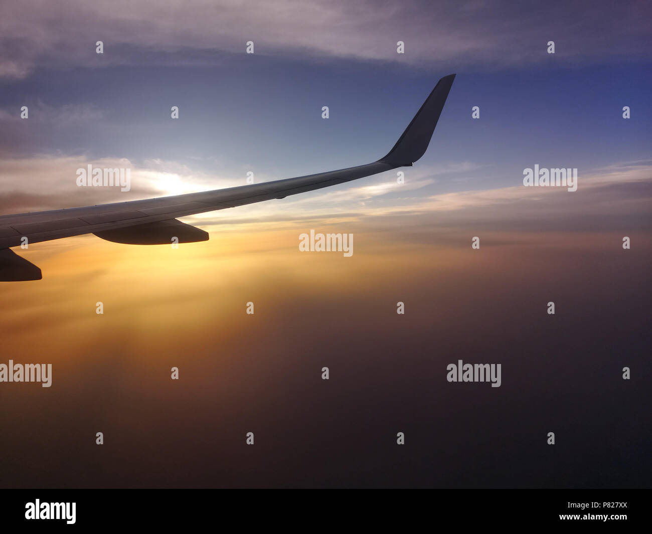 Flugzeugflügel über Himmel bei Sonnenuntergang gegen Sonne gesehen Stockfoto
