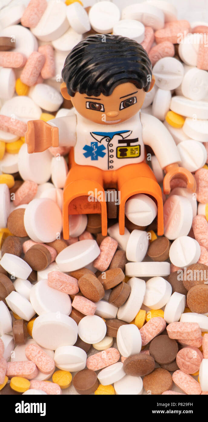 Concept Shot lego Doctor Puppe, umgeben von einem Haufen Pillen und Drogen, die eine Opiod-Krise darstellen Stockfoto