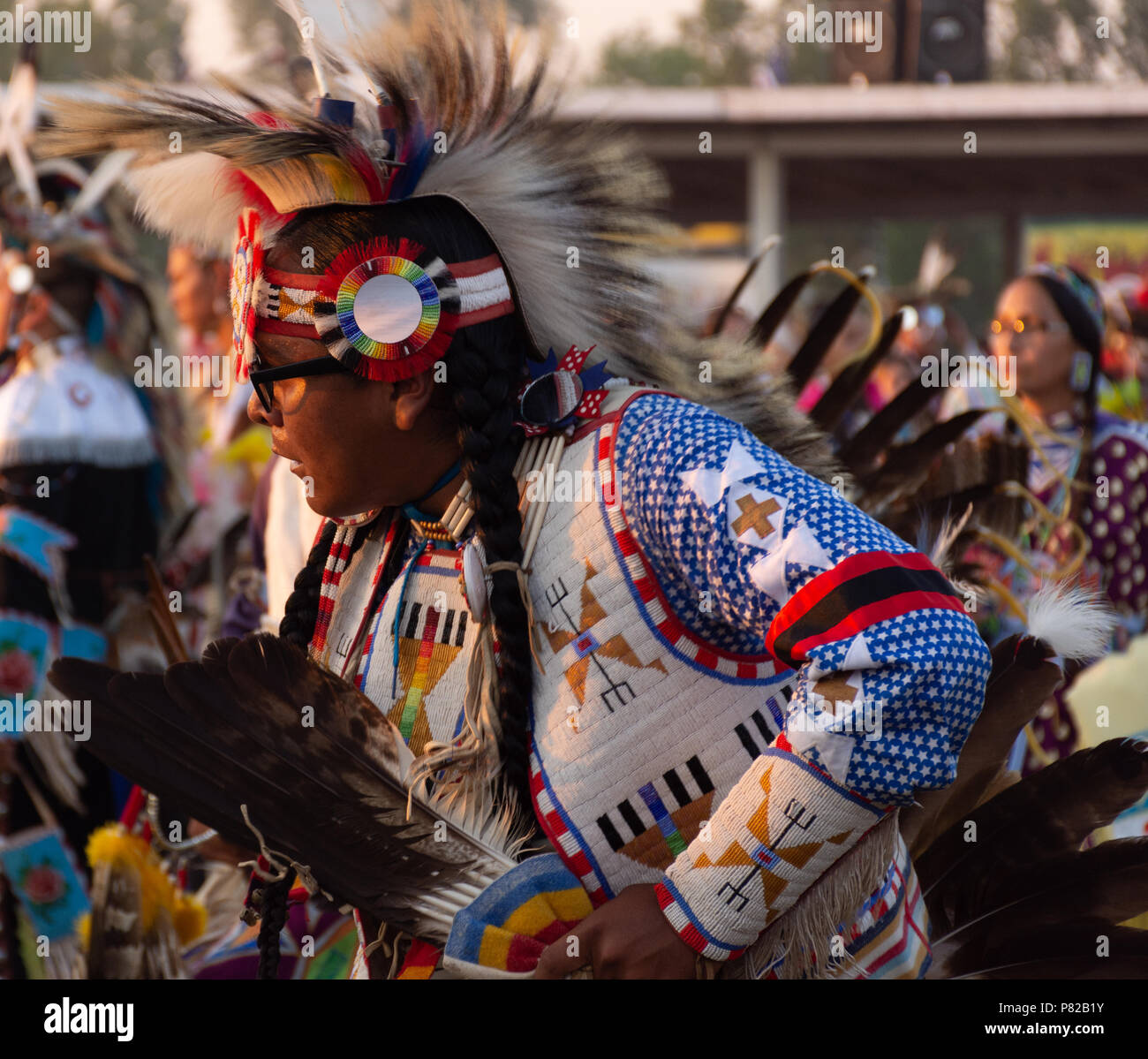 Nahaufnahme einer gebürtigen amerikanischen Mann tanzen in einem Pow Wow trägt ein blaues T-Shirt mit Stern Muster, einer durchgehenden Weste, Fell Kopftuch und einer durchgehenden Stirnband. Stockfoto